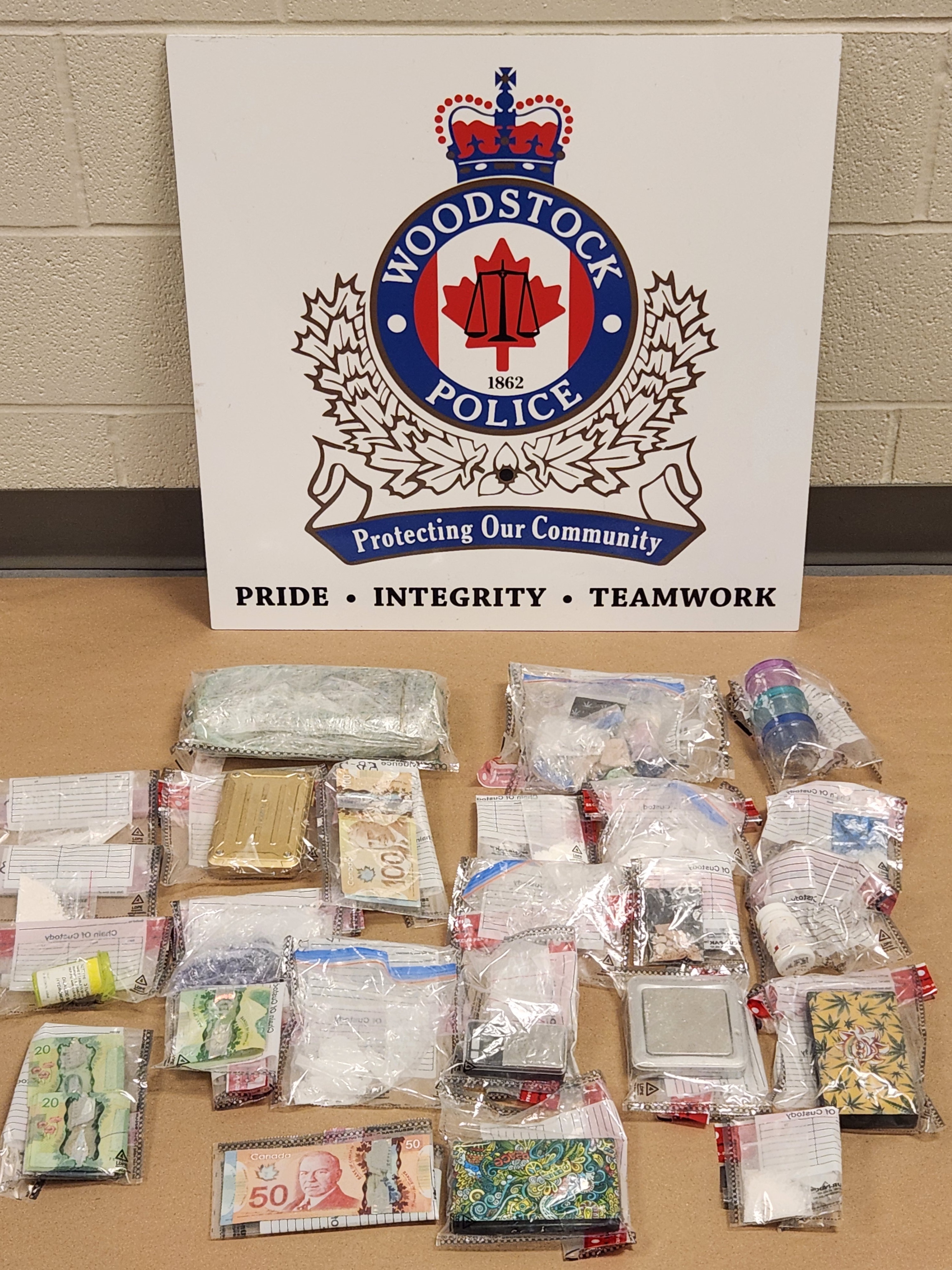 Woodstock Police Service logo behind drugs and cash in evidence bags